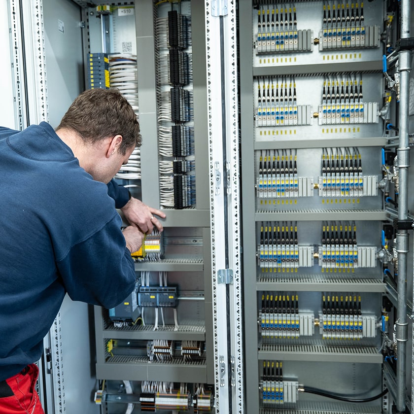 Ein Elektroniker arbeitet an einem Schaltschrank für eine WM 3400 Teilewaschmaschine.