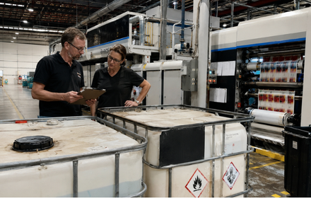 Zwei Mitarbeitende prüfen Chemikalienbehälter in einer Druckerei